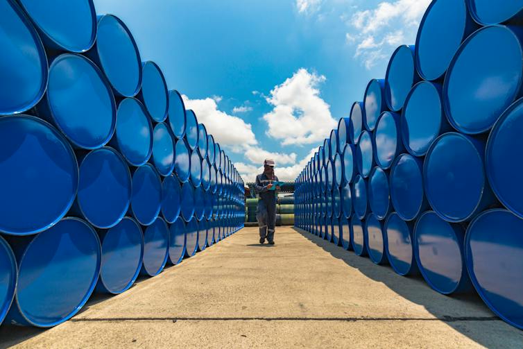 man standing near stacked oil barrels